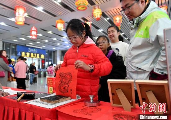 1月14日，福建泉州站候车大厅，小朋友体验木板年画拓印。中新社记者 吕明 摄