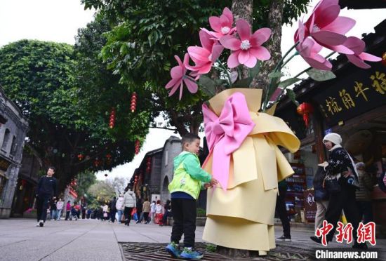 3月17日，福州三坊七巷南后街，街头许多原来光秃秃的树木底部被扮靓成“一束花”，为街区的春天增添了一抹亮色。中新社记者 张斌 摄