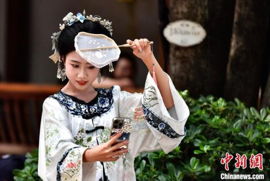 图为5月5日，头戴“三条簪”身着汉服的游客在福州三坊七巷自拍留影。中新社记者 张斌 摄