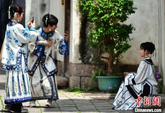 图为5月5日，头戴“三条簪”身着汉服的游客在福州三坊七巷打卡留影。中新社记者 张斌 摄