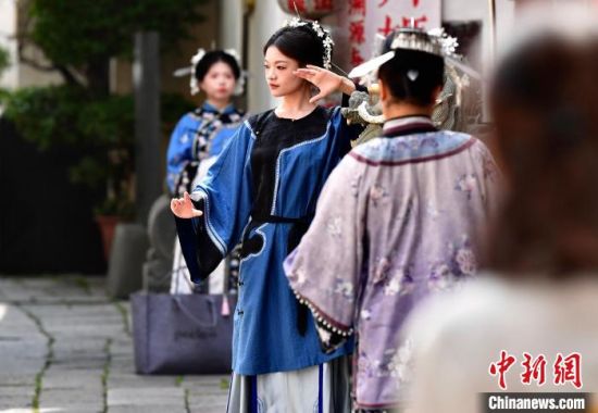 图为5月5日，在福州三坊七巷头戴“三条簪”身着汉服的游客在跟拍摄影师的指导下留影。中新社记者 张斌 摄