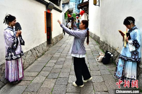 图为5月4日，跟拍摄影师在福州三坊七巷为游客拍摄“三条簪”妆造。中新社记者 张斌 摄